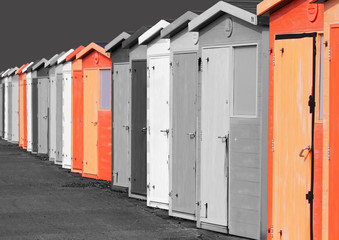 Selective-colour image of a line of beach huts, predominantly black and white.