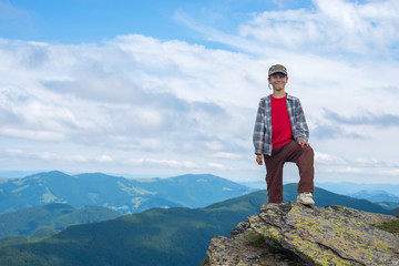 Smiling boy stands on the cliff in the mountain