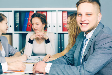 Portrait of smiling business man, with female colleagues on the background. Serious business and partnership, job offer concept.