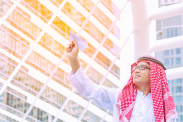 Fototapeta premium Arab businessman with paper airplane. Cheerful Arab businessman dreaming a good life.