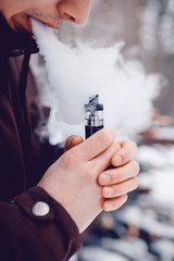 vaping man holding a mod device. cloud of vapor. Vape