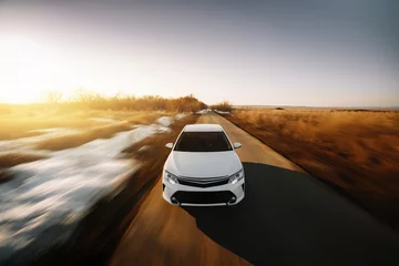 Photo sur Aluminium Voitures rapides White modern car drive at asphalt road at sunset
