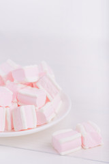 Pastel close-up sweets. Pink and white soft marshmallow on plate on white background