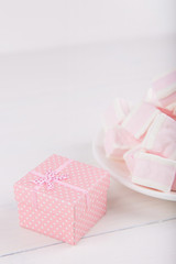 Soft pink and white marshmallow with gift box on white background. Pastel sweets.