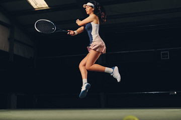 Fototapeta na wymiar Female tennis player in a jump on a tennis court.