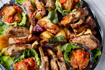 Meat plate with delicious pieces of meat, salad, ribs, grilled vegetables, potatoes and sauce. Top view