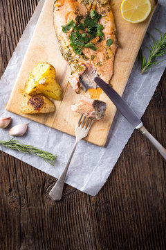 Trout with potateos on wooden board.