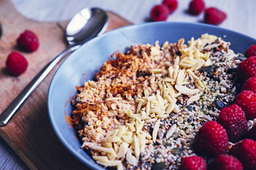 Raspberry, nuts and sunflower seed in a cup on a wooden desk.