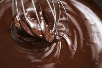 closeup of steel whisk in melted dark premium chocolate