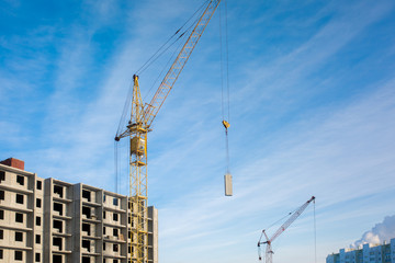 Construction of a new high floor house, using an industrial crane, concrete slabs, building on a blue sky background