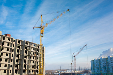 Fototapeta na wymiar Construction of a new high floor house, using an industrial crane, concrete slabs, building on a blue sky background