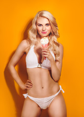 Hot blonde in a white swimsuit with ice cream in hands