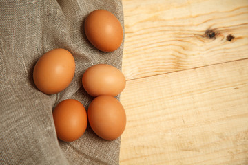 Raw organic brown eggs over linen napkin and rustic wooden background