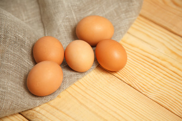 Raw organic brown eggs over linen napkin and rustic wooden background