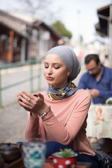  woman wearing hijab enjoying in cup of tea 