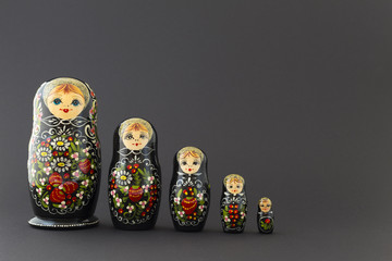 Beautiful black matryoshka dolls with white, green and red painting in front of dark background