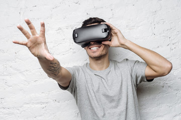 Close up portrait of excited man experiencing virtual reality, using VR headset and touching air...