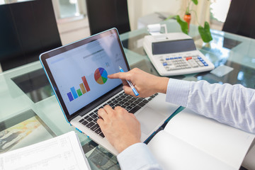 Business man pointing on analysis graph in laptop monitor during working at home