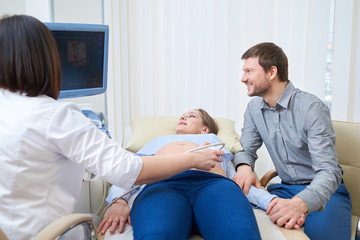 Fototapeta premium Loving couple attending doctor for pregnancy ultra sound procedu