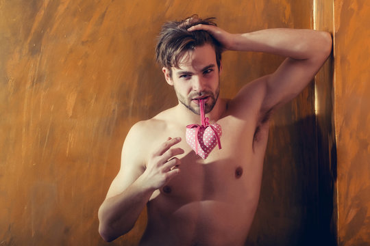 bearded muscular man with sexy body holds pink valentines heart