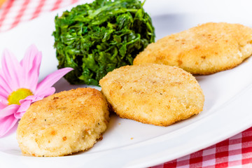 Fish cutlets with stewed spinach on white plate