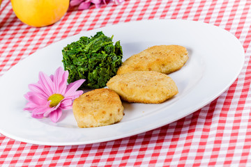 Fish cutlets with stewed spinach on white plate