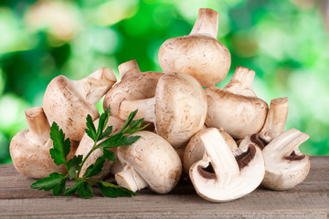 Champignon mushrooms on wooden table with blurred garden background