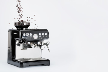 Isolated black manual coffee maker with grinder and falling coffee beans on white background, side view