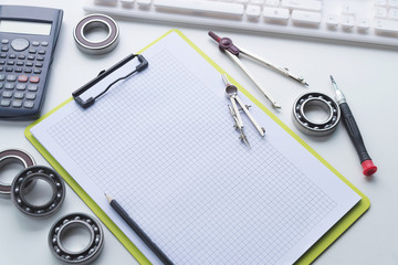 Architecture, engineering and construction background concept. Working desk of engineer, Blueprint rolls, Programmable calculator,dividers,clipboard and pencil on white desk.Selective focus.