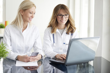 Making an appointment. Shot of a female doctor working together with her assistant in exam room and consulting.