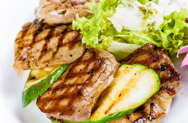 Grilled meat and zucchini on white plate
