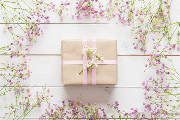 White wooden table with pink flowers and a present, mother's day concept