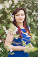 beautiful young brunette woman standing near the blossoming apple tree on a warm spring day