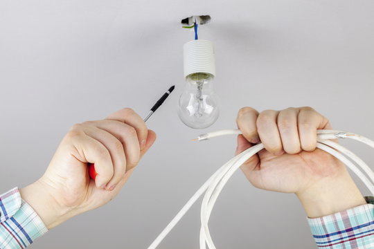Man with screwdriver and wire near to the bulb