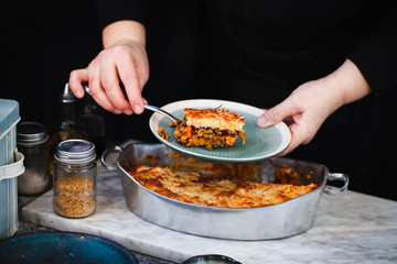 Stuffing casserole with sweet potatoes and beef minced meat. Person serving stuffing casserole. 