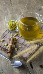 The cup of chamomile tea on wooden table with dried  chamomile in white bowl as background