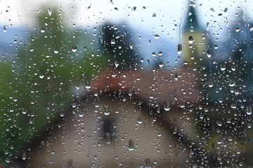 Rain drops on window with house and church in background 