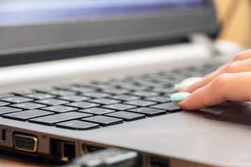 Fototapeta na wymiar Part of the female hand on laptop keyboard. Selective focus