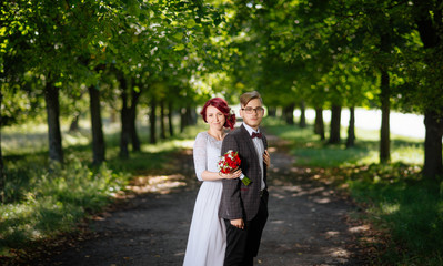 Bride and groom at wedding Day walking Outdoors on summer nature. Bridal couple, Happy Newlywed woman and man embracing. Loving wedding couple outdoor. Bride and groom