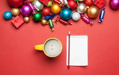 cup of coffee, notebook with pencil and beautiful christmas decorations on the wonderful red background