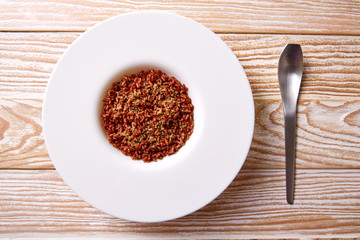 Red wild rice in a white plate over wood