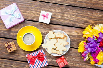 bunch of tulips, cute gifts, plate of cookies and cup of coffee on the wonderful brown wooden background