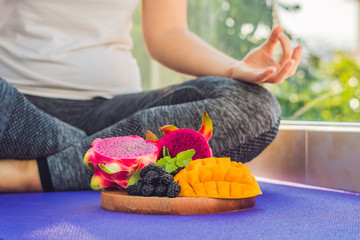 hand of a woman meditating in a yoga pose, sitting in lotus with fruits in front of her dragon...