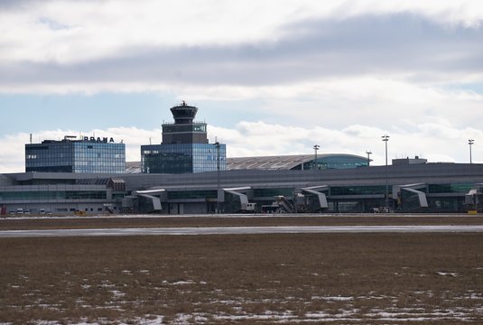 Landscape Picture on the buildings, terminals and control tower of the Vaclav Havel airport in the capitol of Czech Republic Prague. Picture is taken in the winter, cold sunny day with clouds in sky.