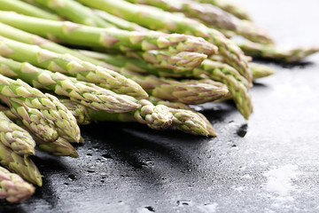 Green asparagus with water drops on black wooden table