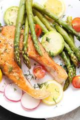 Steak of salmon with asparagus and vegetables on black wooden table