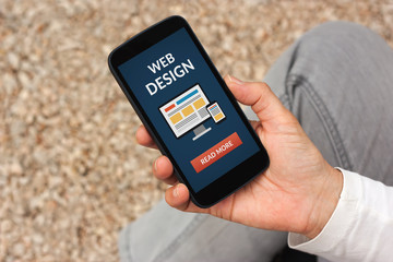 Hand holding smart phone with web design concept on screen. All screen content is designed by me