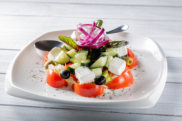 Fresh Greek salad on white plate with onion. Selective focus