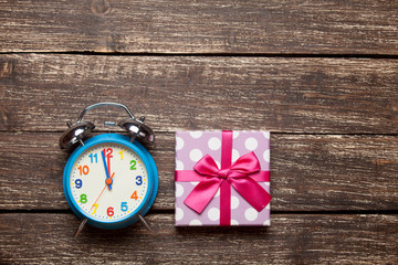 photo of cute wrapped gift and alarm clock on the wonderful brown wooden background
