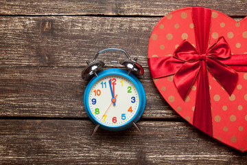 photo of cute wrapped gift and alarm clock on the wonderful brown wooden background